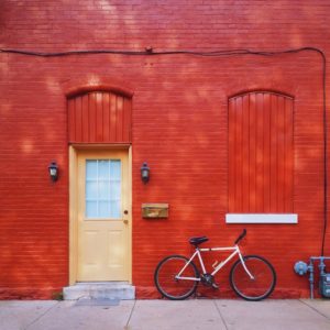 red brick wall, orange door and bicycle